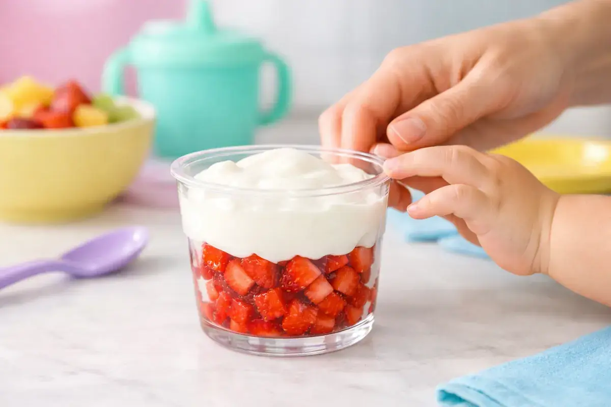Step 4: A small clear toddler cup with a layer of red diced strawberries topped with white yogurt