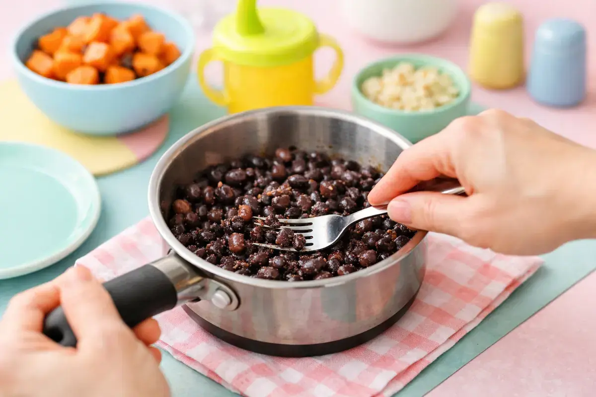 Step 3: Black beans in a small saucepan being lightly mashed with a fork